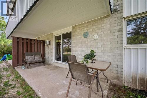 Patio area with concrete surfacing, white brick exterior, wood slat privacy screening, and a sliding glass door - 6 Walton Avenue Unit# 107, Kitchener, ON - Outdoor With Deck Patio Veranda With Exterior