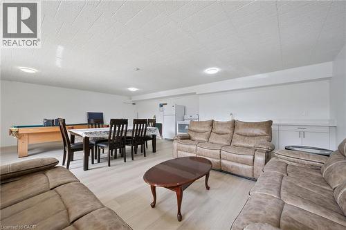 Open-concept living area with wood-finish flooring, recessed lighting, and a built-in wet bar featuring a solid surface countertop and white cabinetry - 6 Walton Avenue Unit# 107, Kitchener, ON - Indoor Photo Showing Living Room