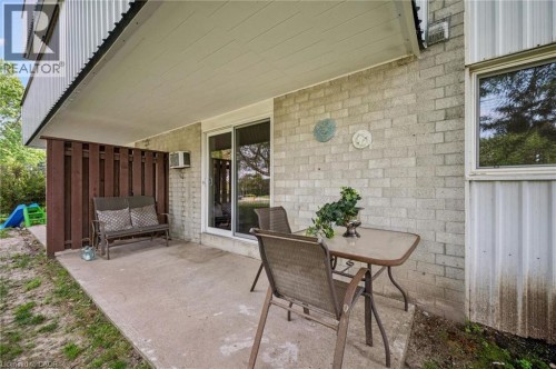 Patio area with concrete surfacing, white brick exterior, wood slat privacy screening, and a sliding glass door - 6 Walton Avenue Unit# 107, Kitchener, ON - Outdoor With Deck Patio Veranda With Exterior