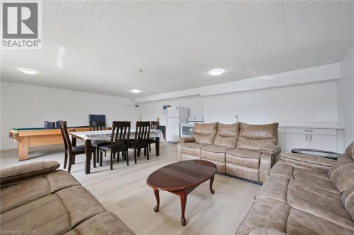 Open-concept living area with wood-finish flooring, recessed lighting, and a built-in wet bar featuring a solid surface countertop and white cabinetry - 6 Walton Avenue Unit# 107, Kitchener, ON - Indoor Photo Showing Living Room