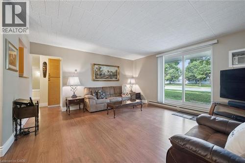 Wood-finish flooring throughout, sliding glass door with blinds, and built-in vertical cabinetry - 6 Walton Avenue Unit# 107, Kitchener, ON - Indoor Photo Showing Living Room