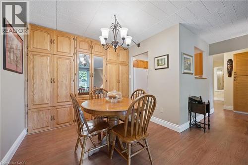 Extensive wood-finish cabinetry, wood-finish flooring, and a chandelier with decorative arms - 6 Walton Avenue Unit# 107, Kitchener, ON - Indoor Photo Showing Dining Room