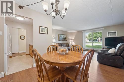 Wood-finish flooring throughout, with a classic chandelier and recessed lighting - 6 Walton Avenue Unit# 107, Kitchener, ON - Indoor Photo Showing Dining Room