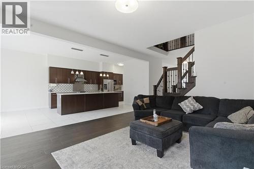 Open-concept living area with wood-finish flooring, a contemporary kitchen featuring dark wood cabinetry, white countertops, and a patterned tile backsplash - 2000 Maddex Way, London, ON - Indoor Photo Showing Living Room