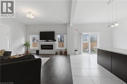 Open-concept living space featuring dark wood-finish flooring, a linear gas fireplace with white surround and built-in cabinetry, a wall-mounted flat-screen television, recessed and pendant lighting, - 2000 Maddex Way, London, ON - Indoor Photo Showing Living Room
