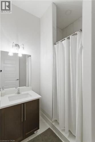 Modern bathroom featuring a dark wood vanity with brushed metal hardware, white quartz countertop, and an integrated sink - 2000 Maddex Way, London, ON - Indoor Photo Showing Bathroom