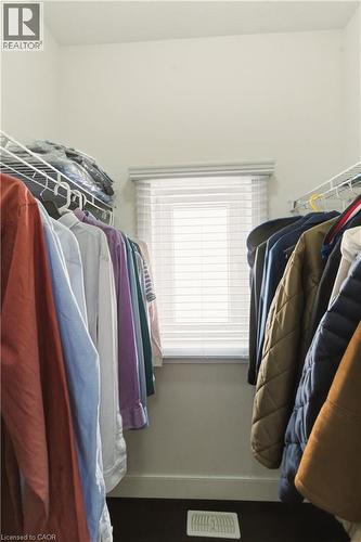 Walk-in closet with wire shelving, a window featuring blinds, and dark wood-finish flooring - 2000 Maddex Way, London, ON - Indoor With Storage