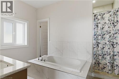 Built-in soaking tub, large vanity with integrated sink and stone-look countertop, tile surround, and an enclosed shower - 2000 Maddex Way, London, ON - Indoor Photo Showing Bathroom