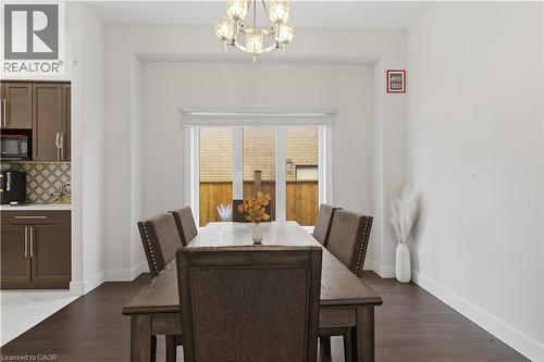 Formal dining space showcasing dark wood-finish flooring, a substantial dining table with upholstered chairs featuring nailhead trim, and a crystal chandelier - 2000 Maddex Way, London, ON - Indoor Photo Showing Dining Room