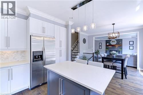 Contemporary kitchen featuring white shaker cabinetry, stainless steel appliances, a white herringbone tile backsplash, and a central island with a light-toned countertop - 1406 Marshall Crescent, Milton, ON - Indoor Photo Showing Kitchen