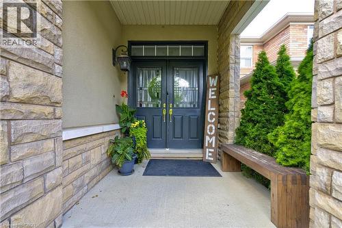 Stone facade entryway with double panel doors, transom window, and an exterior wall light - 1406 Marshall Crescent, Milton, ON - Outdoor