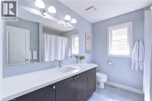 Bathroom featuring a dark wood-finish vanity with a white countertop and integrated sink, a large wall-mounted mirror, overhead lighting, and a window with blinds - 1406 Marshall Crescent, Milton, ON - Indoor Photo Showing Bathroom