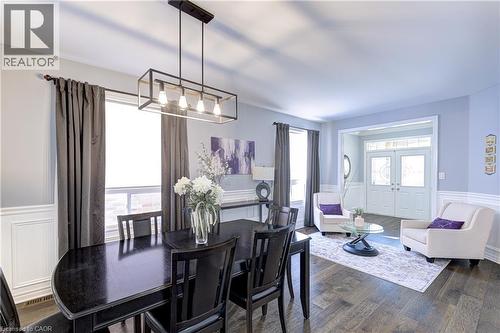 Dining area featuring wood-finish flooring, wainscoting, and an industrial-style linear chandelier - 1406 Marshall Crescent, Milton, ON - Indoor