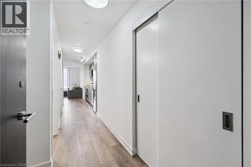 Entryway corridor featuring wood-finish flooring, white walls, recessed lighting, and a modern pocket door with a dark handle - 15 Wellington Street S Unit# 903, Kitchener, ON - Indoor Photo Showing Other Room