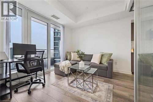 Living area featuring expansive floor-to-ceiling windows, wood-finish flooring, and white walls - 15 Wellington Street S Unit# 903, Kitchener, ON - Indoor Photo Showing Living Room