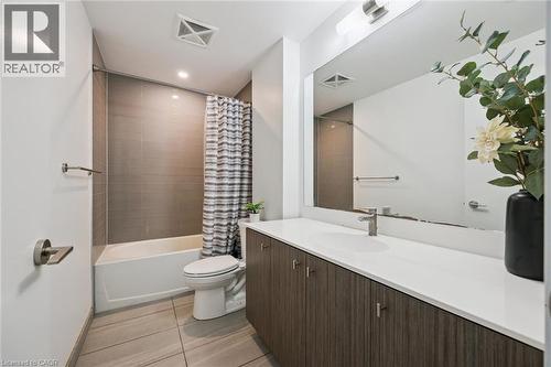 Bathroom featuring a white bathtub, gray tiled shower surround, wood-finish vanity with a white countertop, and a large wall-mounted mirror - 15 Wellington Street S Unit# 903, Kitchener, ON - Indoor Photo Showing Bathroom