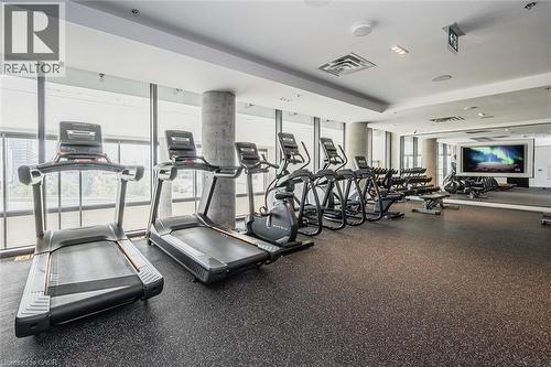 Fitness center featuring floor-to-ceiling windows, rubberized flooring, concrete columns, recessed lighting, and a large wall-mounted screen - 15 Wellington Street S Unit# 903, Kitchener, ON - Indoor Photo Showing Gym Room