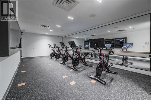 Fitness amenity featuring specialized flooring, mirrored wall, recessed lighting, and wall-mounted screens - 15 Wellington Street S Unit# 903, Kitchener, ON - Indoor Photo Showing Gym Room