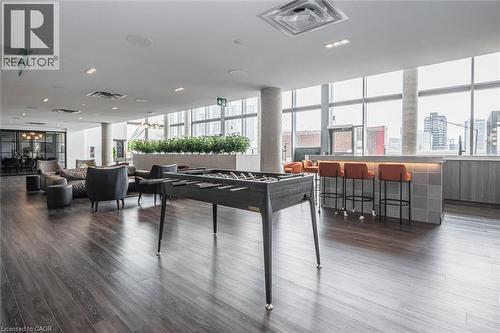 Spacious common area featuring dark wood-finish flooring, a contemporary bar with tiled facade, expansive window walls, recessed lighting, and a foosball table - 15 Wellington Street S Unit# 903, Kitchener, ON - Indoor