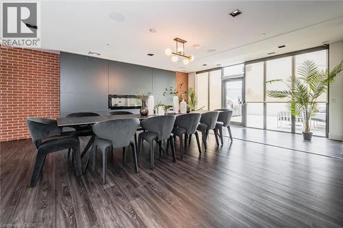 Spacious room featuring dark wood-finish flooring, a full-height exposed brick accent wall, and an integrated linear fireplace - 15 Wellington Street S Unit# 903, Kitchener, ON - Indoor Photo Showing Other Room