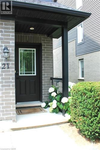 Covered entry with gray brick facade, black front door with glass panel, and exterior lighting fixture - 12 Poplar Drive Unit# 21, Cambridge, ON - Outdoor With Exterior