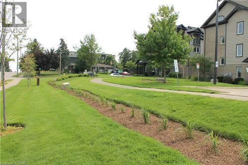 Landscaped green space featuring a paved walkway, mature trees, and planted garden beds - 12 Poplar Drive Unit# 21, Cambridge, ON - Outdoor