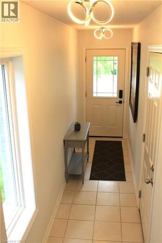 Entryway featuring contemporary ceiling light fixtures, a white paneled entry door with decorative glass, and square tile flooring - 12 Poplar Drive Unit# 21, Cambridge, ON - Indoor Photo Showing Other Room