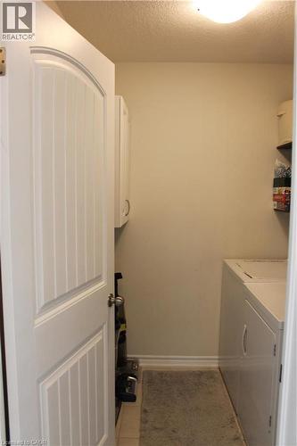 Utility area with built-in cabinetry, wall-mounted shelving, and a permanent ceiling light fixture - 12 Poplar Drive Unit# 21, Cambridge, ON - Indoor Photo Showing Laundry Room