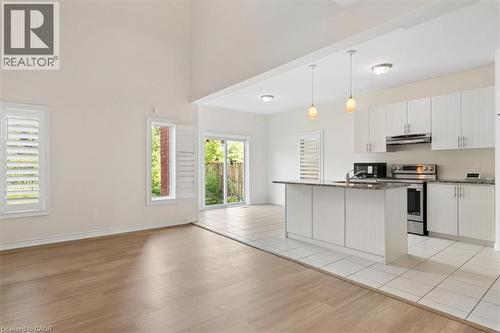 Vaulted ceiling, wood-finish flooring, white plantation shutters, white kitchen cabinetry, and stainless steel appliances - 242 Moorlands Crescent, Kitchener, ON - Indoor Photo Showing Kitchen