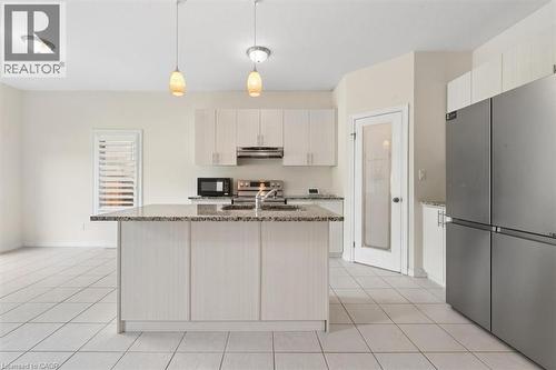 Modern kitchen featuring white shaker-style cabinetry, granite-finish countertops with waterfall island edge, stainless steel appliances including French-door refrigerator, ceramic tile flooring, and - 242 Moorlands Crescent, Kitchener, ON - Indoor Photo Showing Kitchen