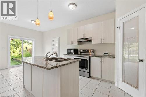 Kitchen featuring an island with an undermount sink, granite-style countertops, white cabinetry, and stainless steel appliances - 242 Moorlands Crescent, Kitchener, ON - Indoor Photo Showing Kitchen With Double Sink With Upgraded Kitchen