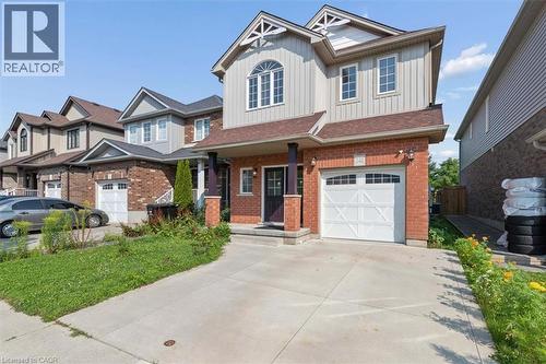 Brick and vertical siding exterior with gabled roof lines, an arched window, and an attached garage with a white panel door - 242 Moorlands Crescent, Kitchener, ON - Outdoor With Facade