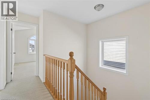 Hardwood staircase with traditional wood balusters, carpeted hallway, arched window, and horizontal blinds - 242 Moorlands Crescent, Kitchener, ON - Indoor Photo Showing Other Room