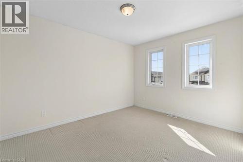 Neutral wall tones, wall-to-wall carpeting, two windows with white trim, and a ceiling-mounted light fixture - 242 Moorlands Crescent, Kitchener, ON - Indoor Photo Showing Other Room