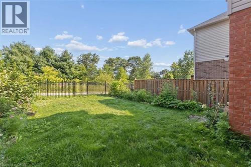 Expansive green space featuring a wood fence, black metal fence, brick exterior, and partial siding - 242 Moorlands Crescent, Kitchener, ON - Outdoor