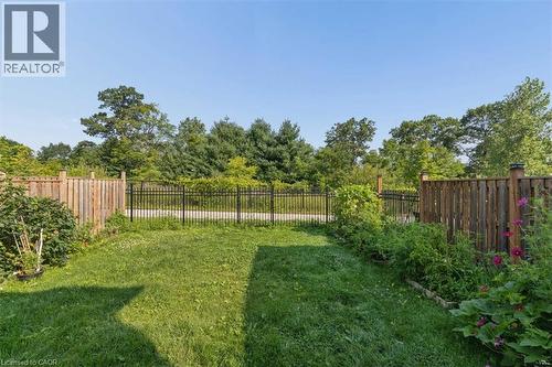 Expansive backyard featuring a manicured lawn, wood fencing, and perimeter plantings - 242 Moorlands Crescent, Kitchener, ON - Outdoor