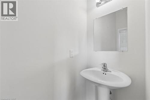 Pedestal sink with a polished chrome faucet, rectangular wall mirror, and overhead vanity light - 242 Moorlands Crescent, Kitchener, ON - Indoor Photo Showing Bathroom