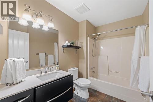 Master Bathroom featuring a single vanity with a white countertop, dark cabinetry, an integrated sink, and a combination shower/tub - 4105 Ross Rd, Nanaimo, BC - Indoor Photo Showing Bathroom
