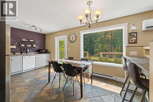 Spacious kitchen featuring slate flooring, white cabinetry, a large picture window, and a built-in breakfast bar - 4105 Ross Rd, Nanaimo, BC - Indoor Photo Showing Dining Room