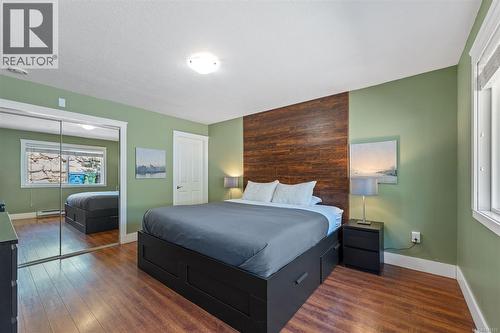 Large Master Bedroom with hardwood-finish flooring, accent wall with wood paneling, mirrored closet doors, recessed window, and an ensuite - 4105 Ross Rd, Nanaimo, BC - Indoor Photo Showing Bedroom