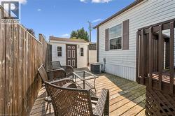 Outdoor deck space featuring wood decking, a privacy fence, an exterior storage shed, and a side window with shutters - 
