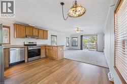 Kitchen featuring stainless steel appliances, wood-finish flooring, and natural wood cabinetry - 