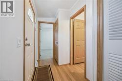 Wood-finish flooring throughout the hallway, paneled interior doors, and a front door with an arched window - 
