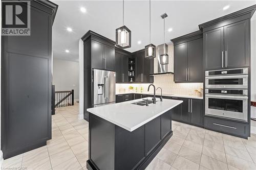 Gourmet kitchen featuring dark cabinetry, stainless steel appliances, a center island with a white countertop, recessed lighting, and tile flooring - 130 Pondcliffe Drive, Kitchener, ON - Indoor Photo Showing Kitchen With Upgraded Kitchen