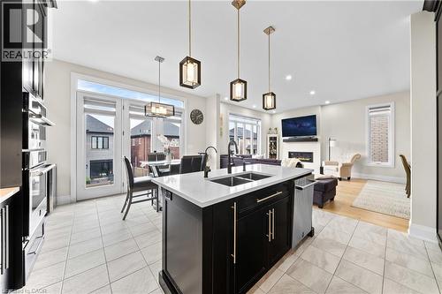 Open-concept living area featuring a kitchen island with a double sink, built-in appliances, a dining area with pendant lighting, and a living room with a fireplace - 130 Pondcliffe Drive, Kitchener, ON - Indoor Photo Showing Kitchen With Double Sink With Upgraded Kitchen