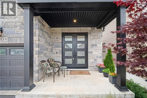 Stone facade with a covered porch featuring black support columns and a dark paneled ceiling - 130 Pondcliffe Drive, Kitchener, ON - Outdoor