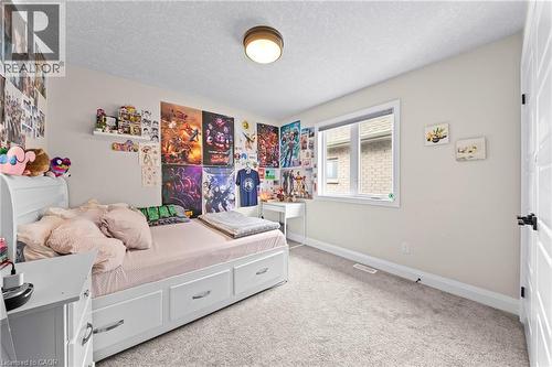 Carpeted room with a double-pane window, flush-mount ceiling light, white baseboards, and a white interior door with black hardware - 130 Pondcliffe Drive, Kitchener, ON - Indoor Photo Showing Bedroom