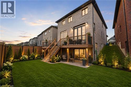Landscaped backyard featuring a manicured lawn, tiered wooden deck, and lower patio area - 130 Pondcliffe Drive, Kitchener, ON - Outdoor