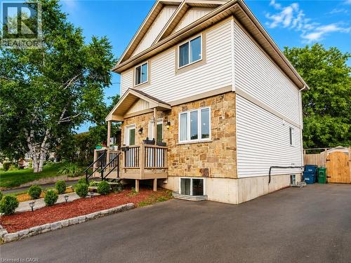Two-story residence featuring stone and siding exterior, front porch with black railing, and mature landscaping - 67 Kinzie Avenue, Kitchener, ON - Outdoor