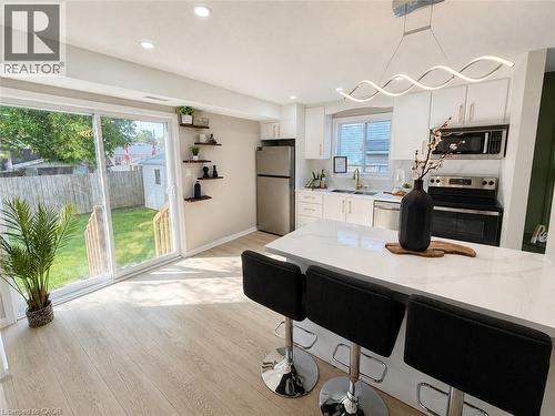 Kitchen featuring a white countertop island, stainless steel appliances, white cabinetry, and wood-finish flooring - 67 Kinzie Avenue, Kitchener, ON - Indoor Photo Showing Kitchen